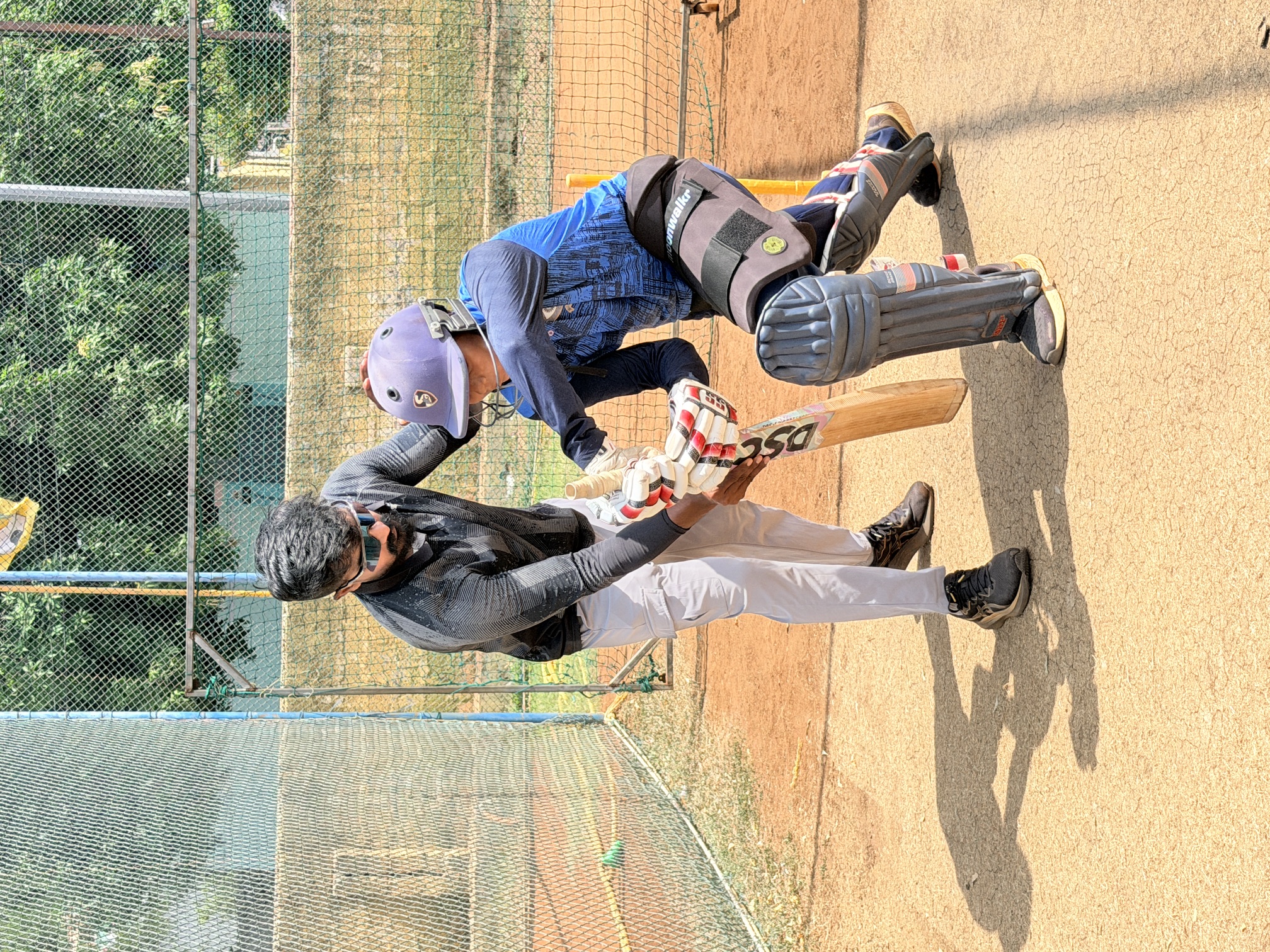 Tarun Teja coaching a young batter in the practice nets