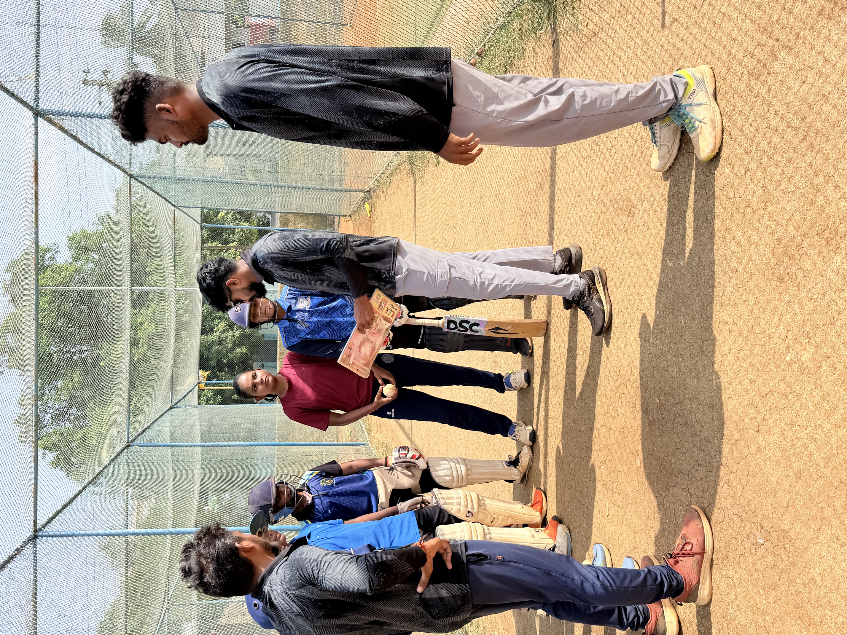 Coaches discussing cricket practice with young players