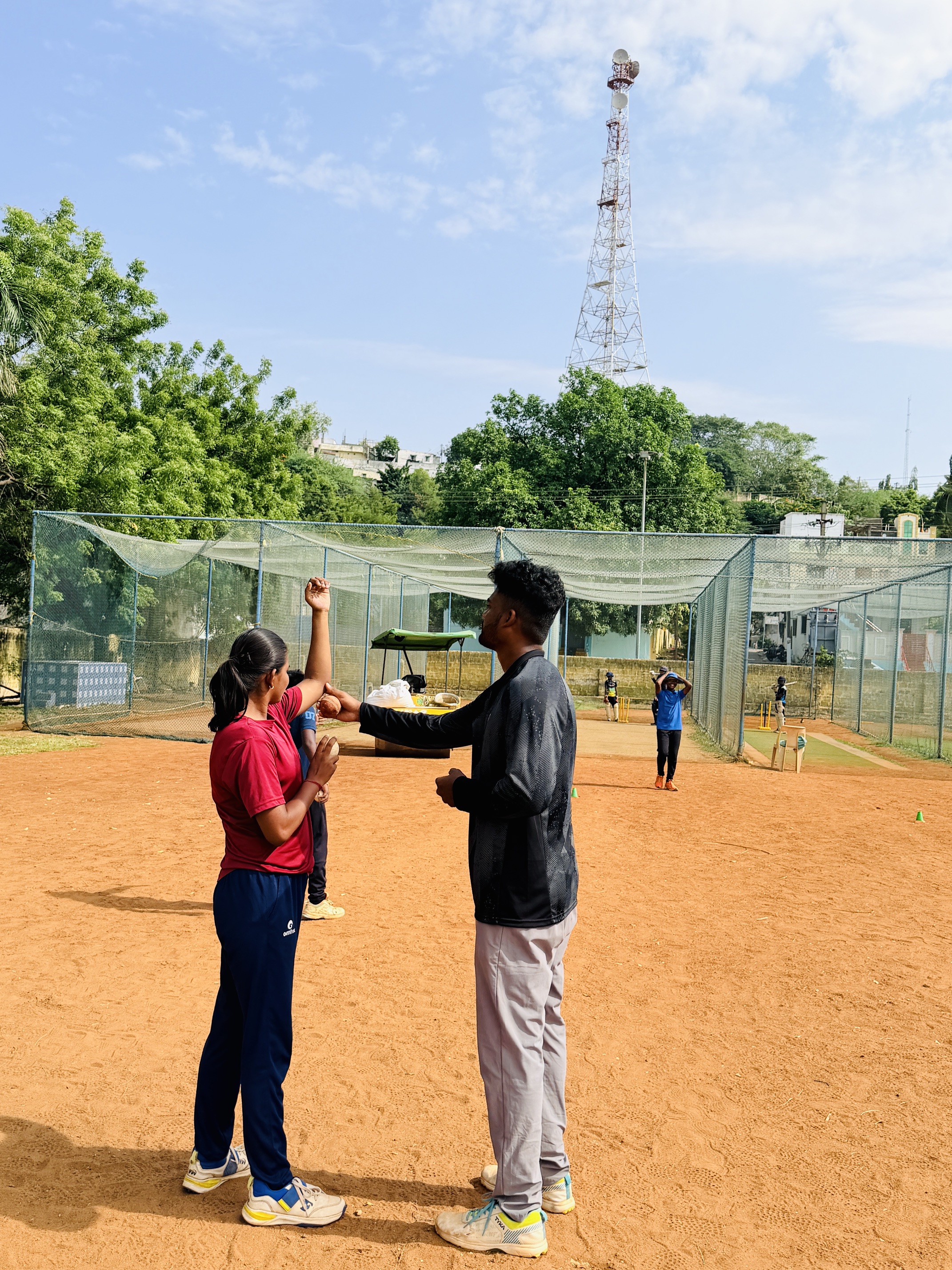 Coach guiding a player during an outdoor cricket training session