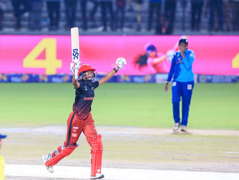 Cricketer raising her bat while celebrating on the field